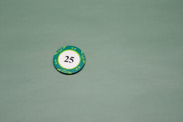 Single one alone green poker chip with value of twenty five isolated on the pastel solid green fond...