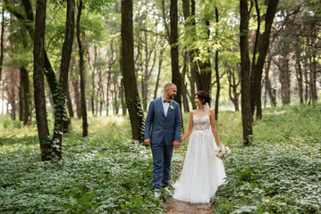 wedding walk of the bride and groom in the deciduous forest in summer