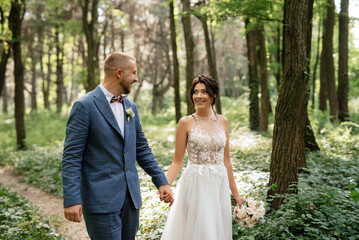wedding walk of the bride and groom in the deciduous forest in summer