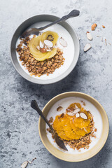 Yogurt granola bowls with kiwi and orange fruits,  top view. Healthy vegetarian breakfast meal