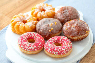 A set of donuts on a plate, glazed with frosting with pink icing and sprinkles.