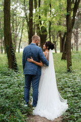 wedding walk of the bride and groom in the deciduous forest in summer