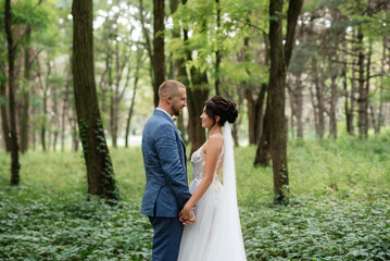 wedding walk of the bride and groom in the deciduous forest in summer