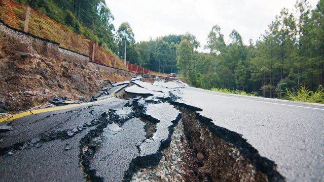 Damaged asphalt road in the mountains. Mudflow aftermath, cracked paved road