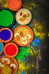 top view of colorful traditional holi powder in bowls isolated on dark background.Space for text . happy holi.Concept Indian color festival called Holi