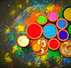 top view of colorful traditional holi powder in bowls isolated on dark background.Space for text . happy holi.Concept Indian color festival called Holi