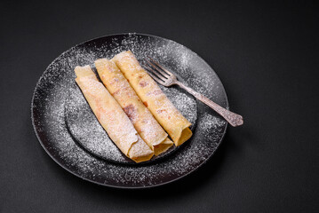 Delicious fresh baked pancakes with honey and fruits on a concrete background