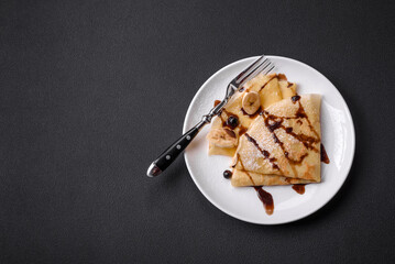 Delicious fresh baked pancakes with honey and fruits on a concrete background