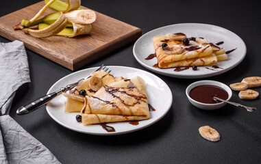 Delicious fresh baked pancakes with honey and fruits on a concrete background