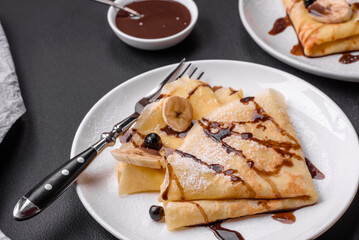 Delicious fresh baked pancakes with honey and fruits on a concrete background