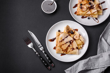 Delicious fresh baked pancakes with honey and fruits on a concrete background