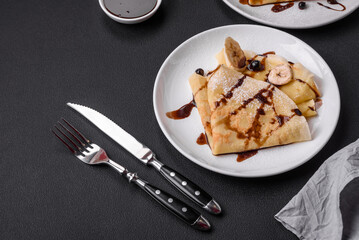 Delicious fresh baked pancakes with honey and fruits on a concrete background