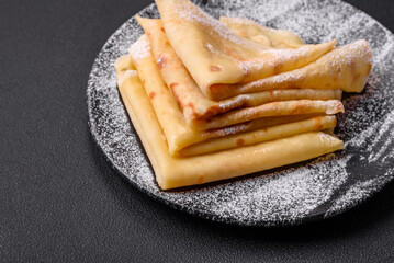 Delicious fresh baked pancakes with honey and fruits on a concrete background