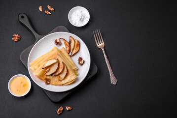 Delicious fresh baked pancakes with honey and fruits on a concrete background