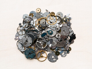 top view of pile of old spare parts for mechanical watches closeup on wooden table in watchmaker workshop