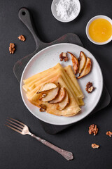 Delicious fresh baked pancakes with honey and fruits on a concrete background