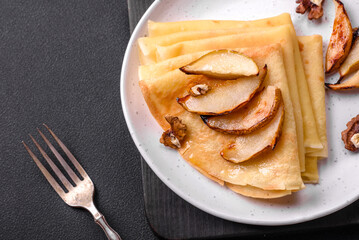 Delicious fresh baked pancakes with honey and fruits on a concrete background