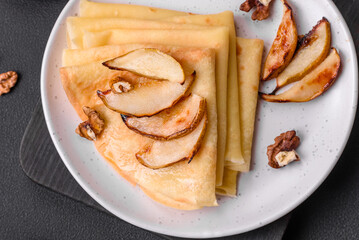 Delicious fresh baked pancakes with honey and fruits on a concrete background