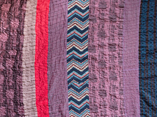 textile background - hand stitched patchwork cloth from various fabric stripes