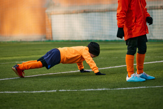 Little boy, child, football player training with professional coach outdoors on sport field. Doing push up exercises. Concept of sport, childhood, active lifestyle, hobby, sport club