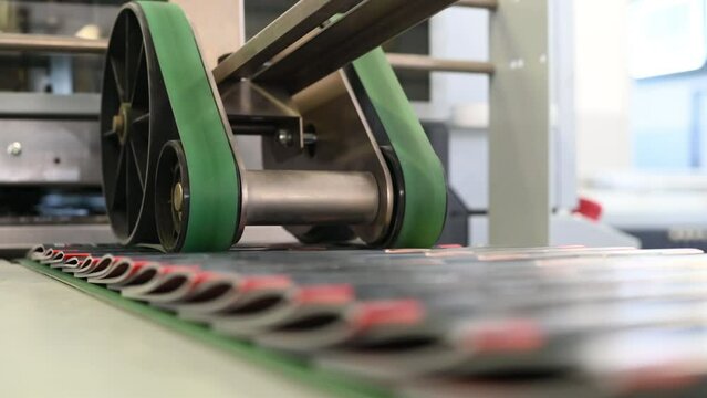 Real time of staple machine binding brochures then wheel rolling it on conveyor belt in manufacturing plant 