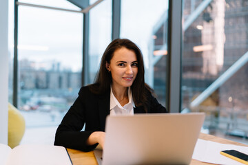 Smiling businesswoman working on laptop in office