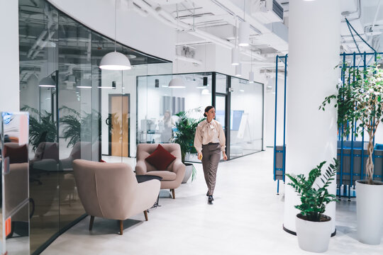 Young Woman Walking In Corridor Of Modern Office