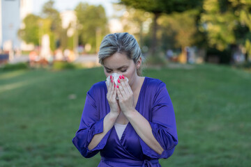 Fototapeta premium Cold and flu. Young attractive woman, caught a cold, wipes her nose with a napkin.