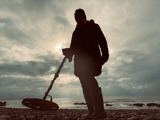 metal detecting silhouette of woman on beach with metal detector searching 