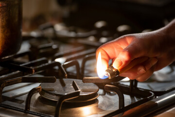 Igniting a gas lighter in a gas stove - obrazy, fototapety, plakaty