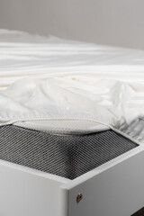 Fototapeta na wymiar White satin sheet on an elastic band on the mattress. Bed linen on the bed