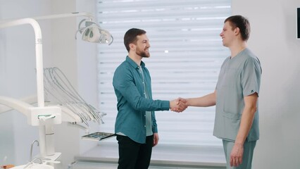 happy patient greets and shakes hand with dentist doctor in dentistry