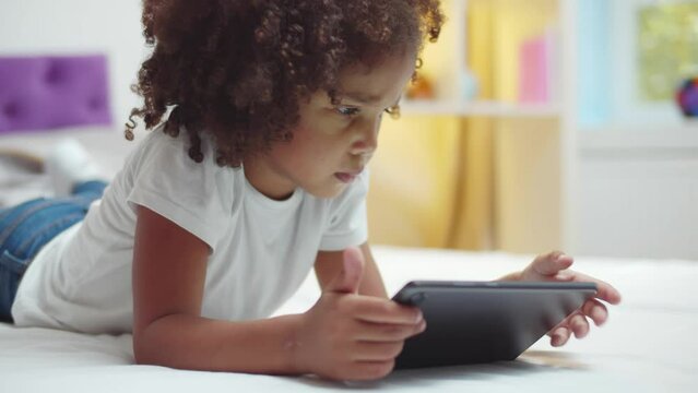 African-American little girl uses digital tablet. Realtime