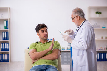 Young male patient visiting old male doctor in vaccination conce