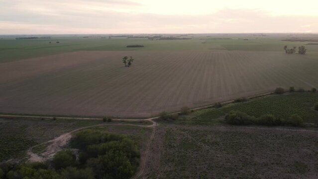 Plano descendente de un campo sin sembrar en un atardecer y aparece un r&iacute;o