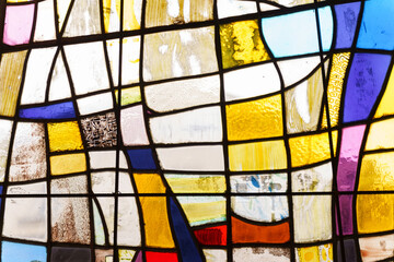 The texture of a glass stained glass window with shades of yellow, blue, purple, white and red.