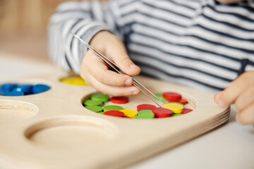 Close up of a little boy learning motor skills and colors by playing with montessori toy.