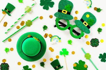 St Patricks Day decorations on white table. Eye glasses, leprechauns hat, drinking straws, confetti. Flat lay, top view