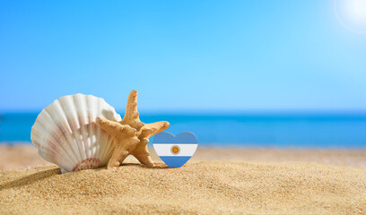 Beautiful beach in Argentina. Flag of Argentina in the shape of a heart and seashells on a sandy beach