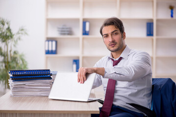 Young male employee and too much work in the office