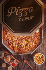 Pizza with mozzarella, bacon, corn, boiled eggs and oregano in a delivery box - Top view.