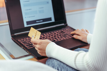 Shopping online. Young girl typing paying with credit or debit card using laptop at home. E-commerce, market. Easy payment