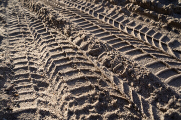 Vehicle tire tracks in the sand on a sunny day