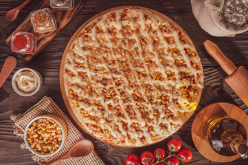 Brazilian pizza with tomato sauce, mozzarella, corn, catupiry and oregano (Pizza de milho especial) - Top view.