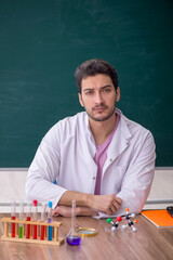 Young male chemistry teacher sitting in the classroom