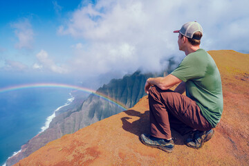 Man looking at Na Pali coast sea cliffs in State Park Kauai Hawaii USA - 574789373