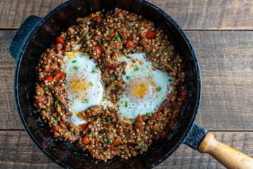Boiled buckwheat with fried eggs, red peppers, carrots and onions, closeup, Ukraine. Food background. Healthy food