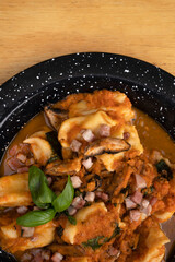 Pasta. Top view of traditional stuffed angelottis with a tomato sauce with mushrooms, bacon and basil.