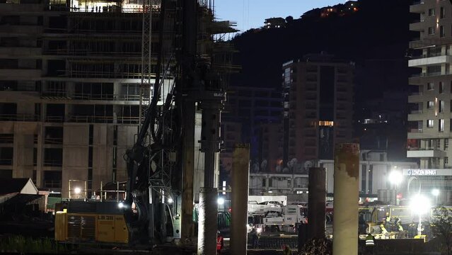 Drilling machine installs piles at a construction site under illumination at night