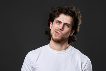 skeptic and nervous man in white t-shirt on dark gray background
